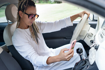 Portrait of rasta woman in a car checking her phone