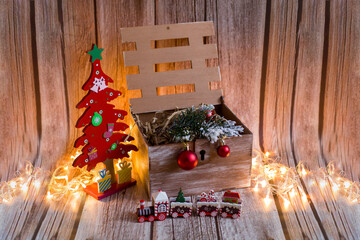 Wooden box with Christmas gifts. Christmas train with lights. Festive lights. The Christmas tree is red.