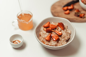 Bowl of oatmeal porridge with strawberry and almond flakes on table. Healthy lifestyle, healthy eating, dieting concept