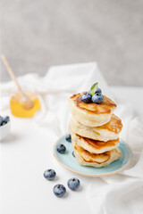 Tasty pancake with fresh blueberries and syrup stacked in stack on gray background