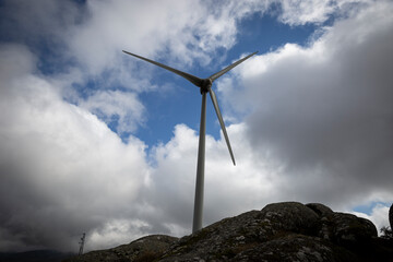 a wind turbine (Renewable Energy) behind a boulder on a cloudy day