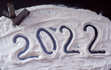 New Year's Eve 2022 is written in flour, next to cookies.