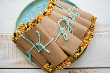 Healthy granola bars with nuts, seeds and dried fruits on a blue plate on a white wooden background. Front view , with copy space. Homemade healthy snack , concept superfood , active lifestyle, sports