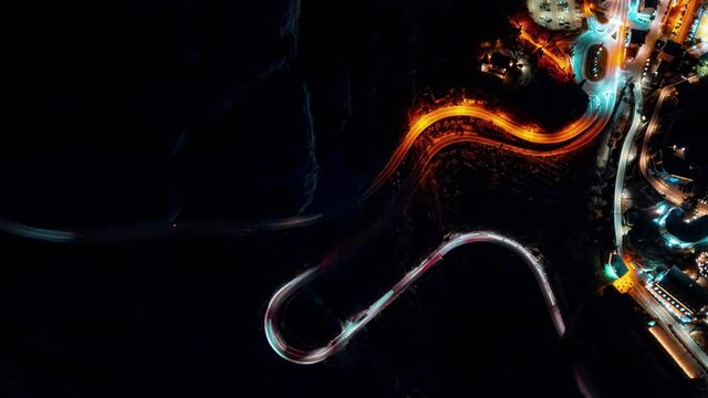 Aerial top down drone night timelapse above the winding mountain road between the trees near Nago and Lake Garda, Italy.