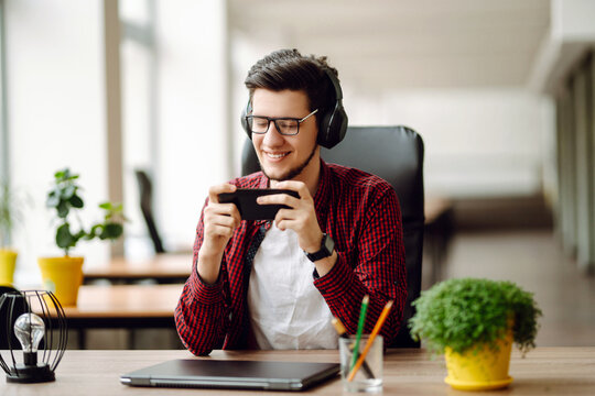 Creative man looking at screen typing message with smartphone. Young man relaxing using laptop computer working and video conference meeting. Business concept.