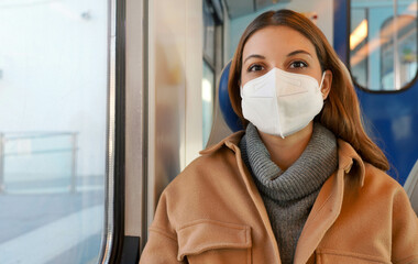Travel safely. Young woman with KN95 FFP2 face mask looking at camera. Passenger sitting on train...