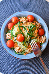 colorful salad with cherry tomatoes, zucchini noodles, carrots and walnuts