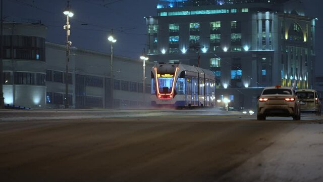 Winter, nighttime cityscape modern tram rides across the bridge in winter