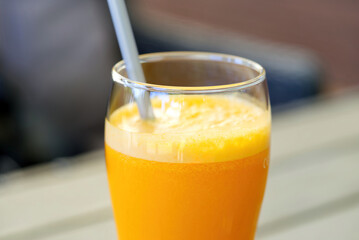 a glass of orange juice on a table at an outdoor bar close up