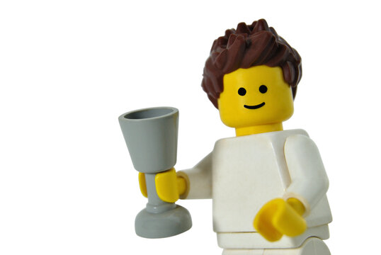 Retrato de um boneco de lego com um copo ou taça na mão - símbolo de jovem a conviver ou a beber - brindar - macrofotografia - tronco branco - cabelo espetado de cor castanha
