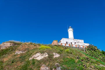Fototapeta na wymiar Lighthouse of Anzio, beautiful detail of the white structure on top of the hill next to the ruins of Nerones villa in summer, with blue sky. Rome Italy.