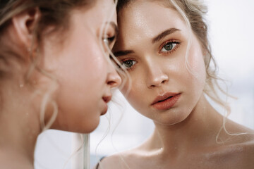Woman Look at Reflection in Mirror Closeup Photo. Blonde Hair Sensitive Girl Examining Face Beauty Makeup in Bathroom. Serious European Fashionable Lady with Perfect Skin Thinking about Relationship