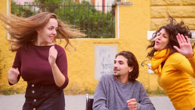 slow motion on affectionate friends entertaining their friend with a disability by making him dance with them