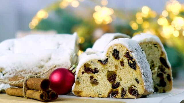 Traditional festive European pastry with raisins, nuts, dried fruit and marzipan. Christmas stollen pie with cinnamon, red ball and Christmas lights. Recipe of homemade dessert for holiday season.