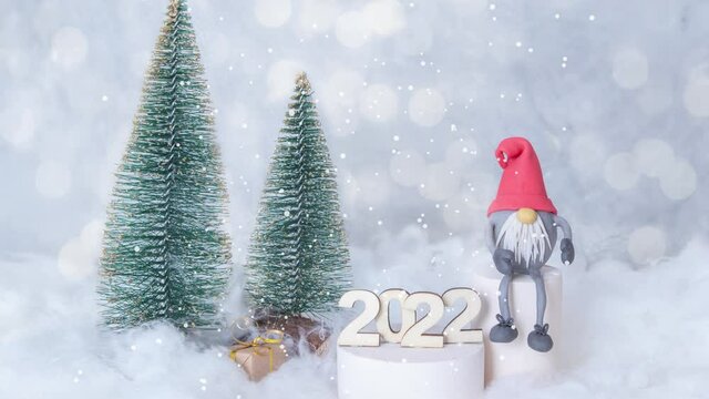 New Year 2022 animated background with flying snow on a snowy background with gnome and Christmas trees