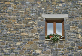 Stone facade with window detail decorated with white flowers.