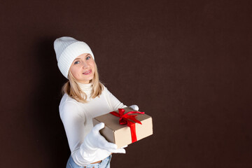 Woman with a gift in her hands on a dark background. Young woman in white hat and gloves