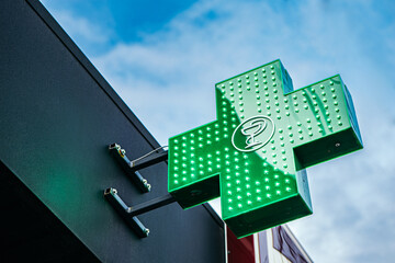 Neon medical bright shining glowing green illuminated urban pharmacy drug store cross sign light...