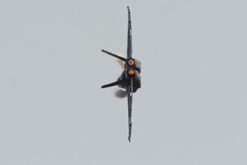 Tail view of a F-18 Hornet in a high G maneuver, with condensation streaks at the wing roots and...