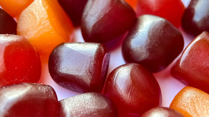 Selective focus.Close-up texture of red, orange and purple multivitamin gummies on white background - obrazy, fototapety, plakaty