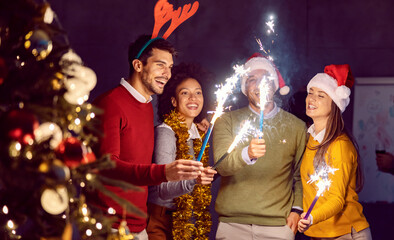 New Year and Christmas celebration. A small group of multicultural friends standing in the office and having a good time on New Years's eve.