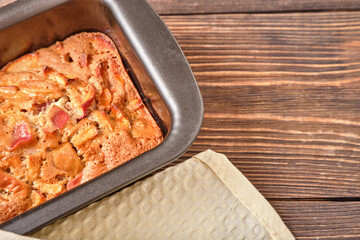 Apple pie in a baking tray on a brown wooden table. Apple charlotte. Homemade apple pie. Close-up,...