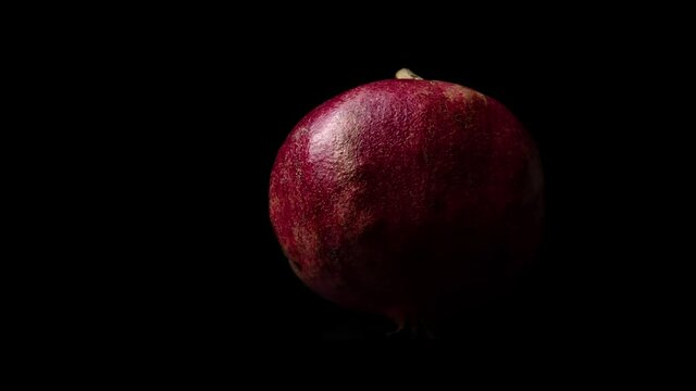 Pomegranate On A Black Background. This stock video features a close up view of pomegranate rotating slowly on a black background.