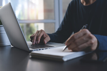 E-learning, teleworking concept. Man working on laptop computer at home office, working from home concept
