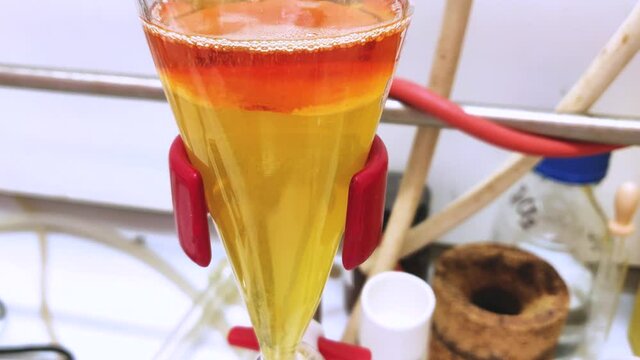 Separation of organic layer and water layer in separating funnel in a chemistry lab for education purpose. Effervescent of carbon dioxide bubble in organic layer. 4K scientific background concept.
