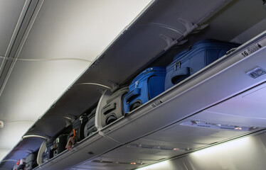 Carry on luggage stuffed in a overhead bin of an airplane 