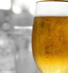 Glass of beer against blurred light background. 