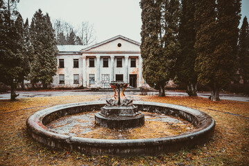 Old, historical, abandoned building Baldone sanatorium and non - working fountain with fish sculptures, Latvia - obrazy, fototapety, plakaty