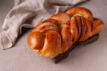 on a wooden board lies a bun with cinnamon