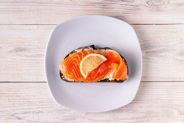 sandwich with cheese, salted trout, lemon on a white wooden background