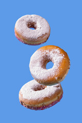 Donuts in powdered sugar fly on a blue background