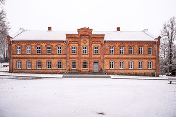 Old red brick school in snowy winter day, Vecumnieki, Latvia