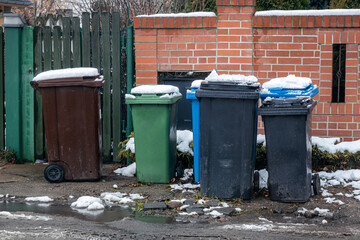 Garbage cans overflowing with rubbish near the house.