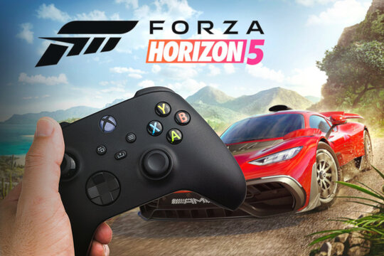 Man holding a Xbox Series S Carbon Black Controller with Forza Horizon 5 game blurred in the background. Rio de Janeiro, RJ, Brazil. December 2021