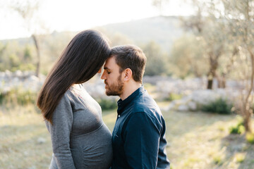 Man leaned his forehead against the forehead of pregnant woman. Portrait