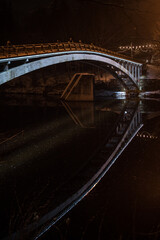 Naklejka premium The arched bridge over the Ogre River in the winter evening is illuminated, Ogre, Latvia