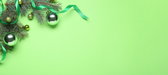 Fir tree branches with Christmas balls on green background with space for text