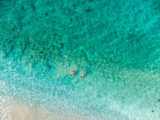 Aerial drone view of swimmers in the sea at summer. Tourists diving and swimming in the water. Transparent sea water in bay.