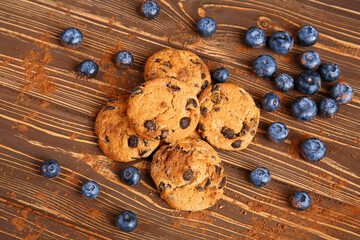 Tasty chocolate chips cookies with bilberries on wooden table