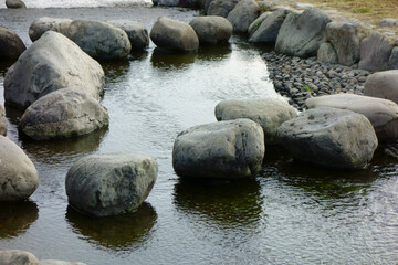 Fototapeta na wymiar 大河の河原に設けられた公園の小川のせせらぎと置石