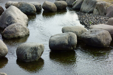 大河の河原に設けられた公園の小川のせせらぎと置石