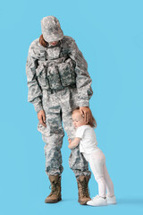 Female soldier with her little daughter on color background