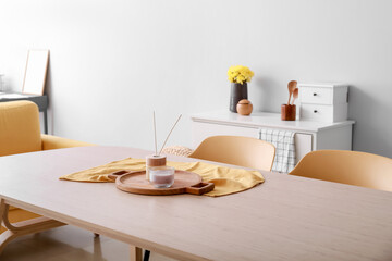 Dining table with reed diffuser and candle in interior of light room