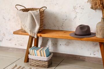 Fototapeta na wymiar Wooden bench with baskets, hat and vase near light wall