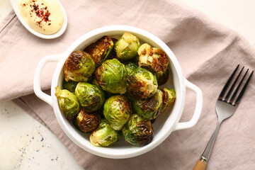 Pot with tasty roasted Brussels cabbage and sauce on light background