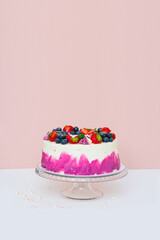 Delicate cake decorated with fresh berries, strawberries and blueberries on a light plain background